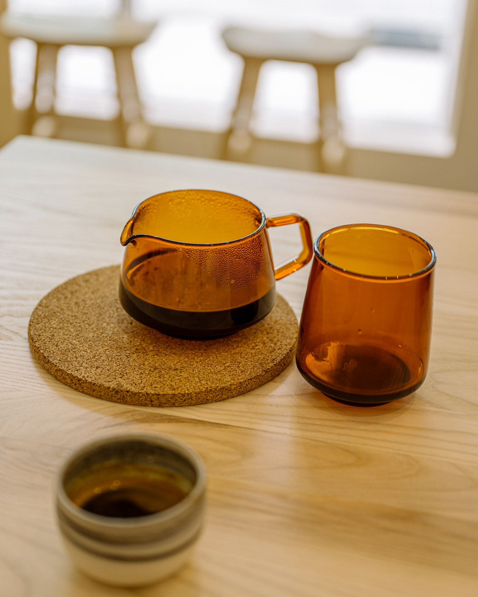 Pour over coffee in a transparent amber glass mug, on a wooden table at deTerroir café in Quebec City
