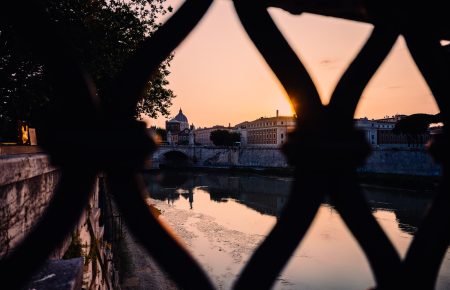 Looking through Ponte Sant'Angelo (Pedestrian bridge, built in 134 A.D., with travertine marble fascias & spanning the River Tiber.) fence, sunset landscape in Rome, Italy